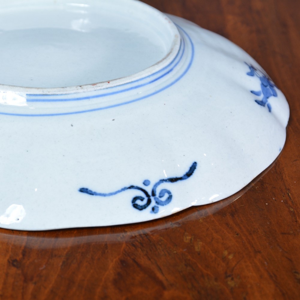 A 19th-century Japanese Imari porcelain circular dish featuring a scalloped rim, central blue medallion, and panelled floral decoration in iron red, cobalt blue, and green enamels. View V