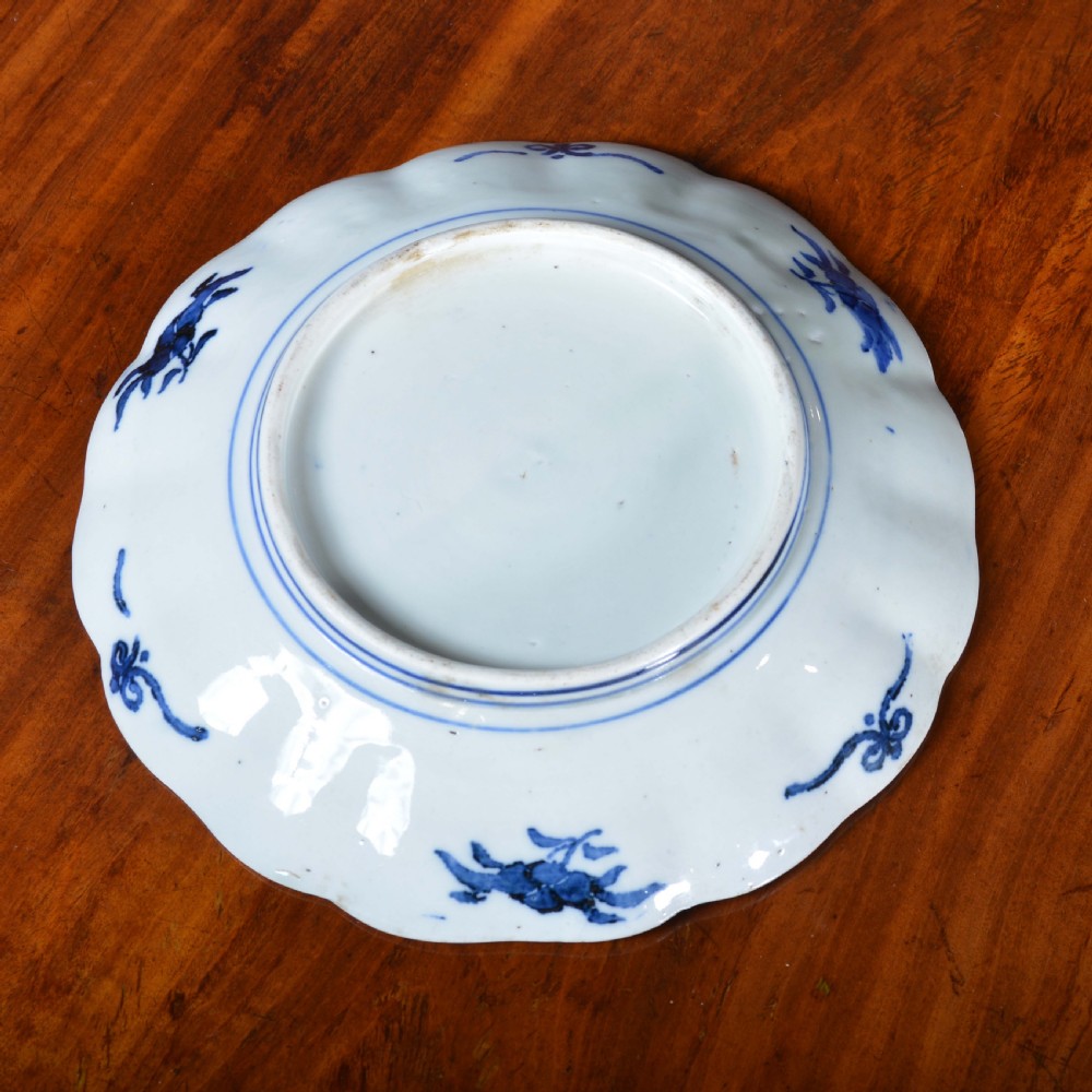 A nineteenth-century Japanese Imari porcelain plate featuring scalloped edges and hand-painted panels of goldfish and floral sprays around a circular central motif in blue and red. View IV