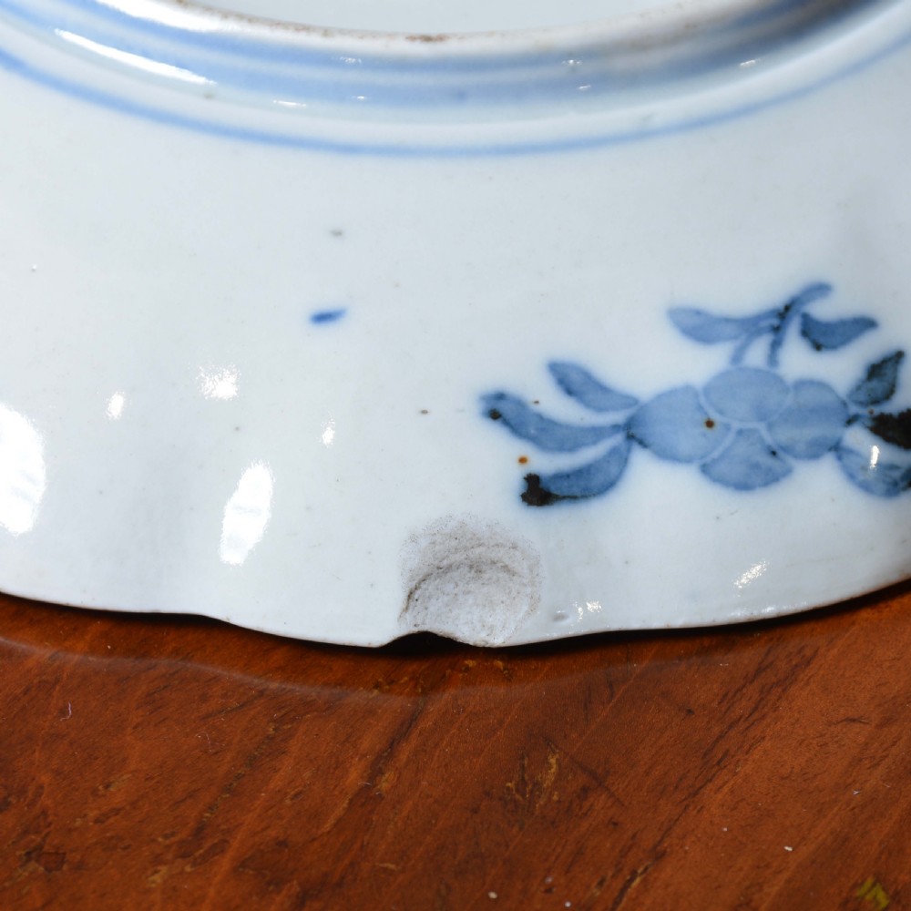 A circular 19th-century Japanese Imari porcelain plate featuring a scalloped rim, hand-painted rust-red and cobalt-blue floral motifs, and a central blue medallion. View III