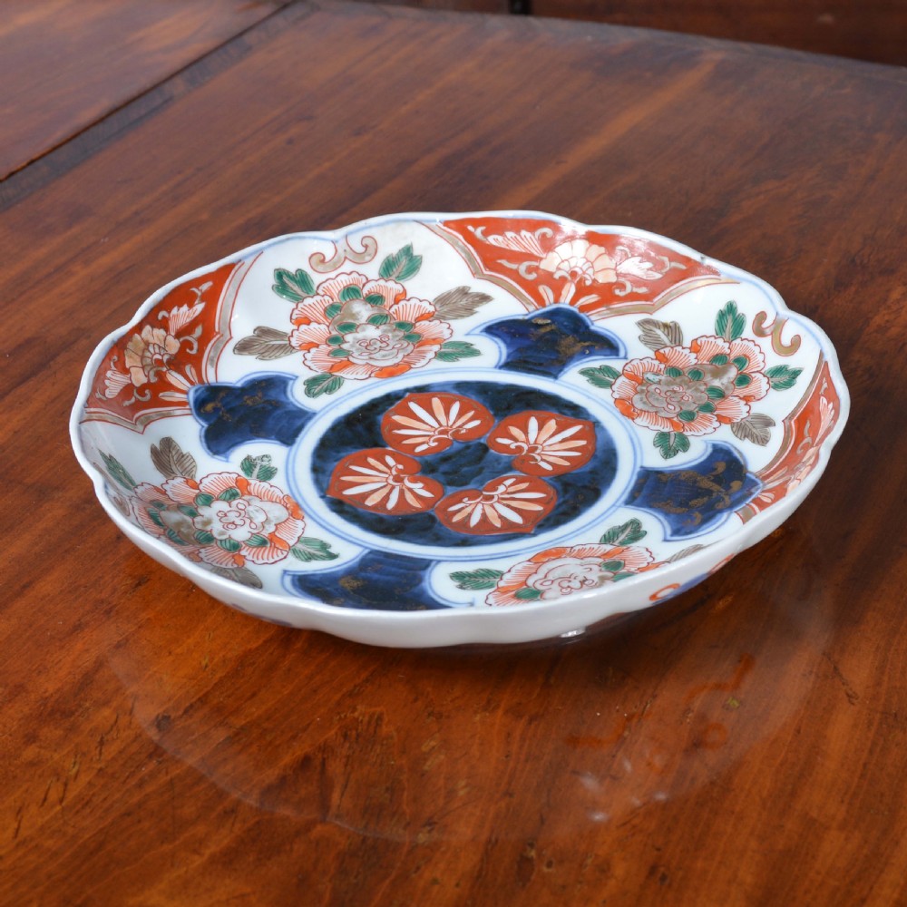 A nineteenth-century Japanese Imari porcelain plate featuring a scalloped rim, hand-painted floral motifs in iron red and green enamels, and cobalt blue brushwork with gold detailing. View II