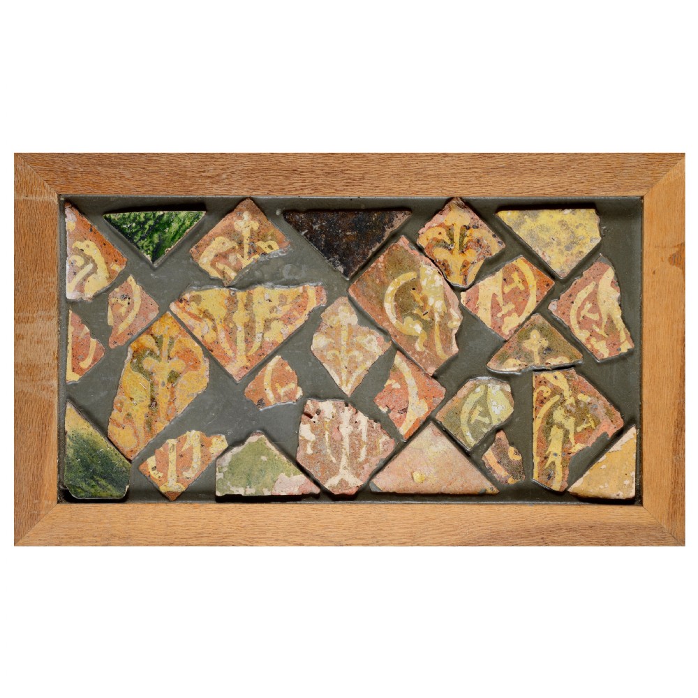 A rectangular panel displaying geometric fragments of medieval terracotta tiles with yellow slip inlaid motifs mounted in a dark backing matrix. View II