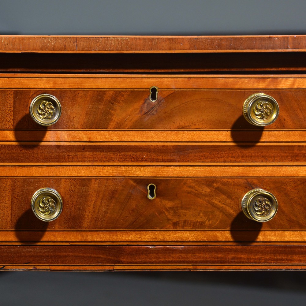 An antique Sheraton style mahogany bowfront side table with stringing inlay, brass handles, and square tapered legs. View V