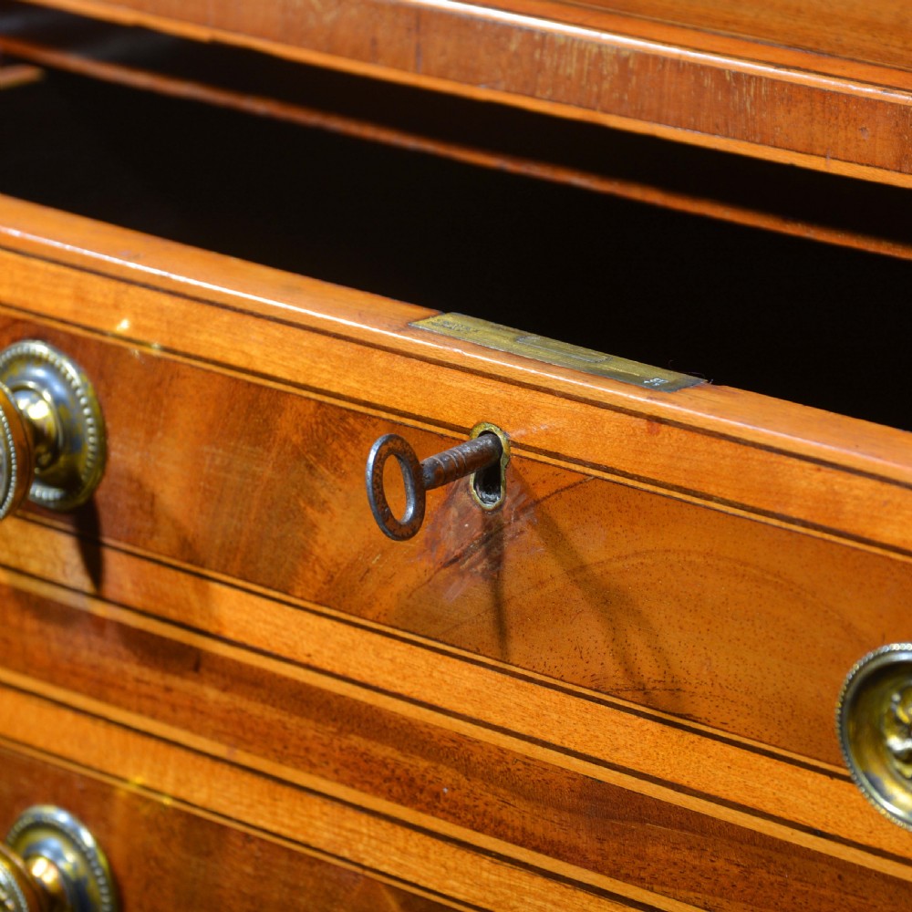An antique Sheraton style mahogany bowfront side table with stringing inlay, brass handles, and square tapered legs. View VII