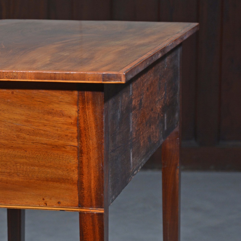 An antique Sheraton style mahogany bowfront side table with stringing inlay, brass handles, and square tapered legs. View VIII