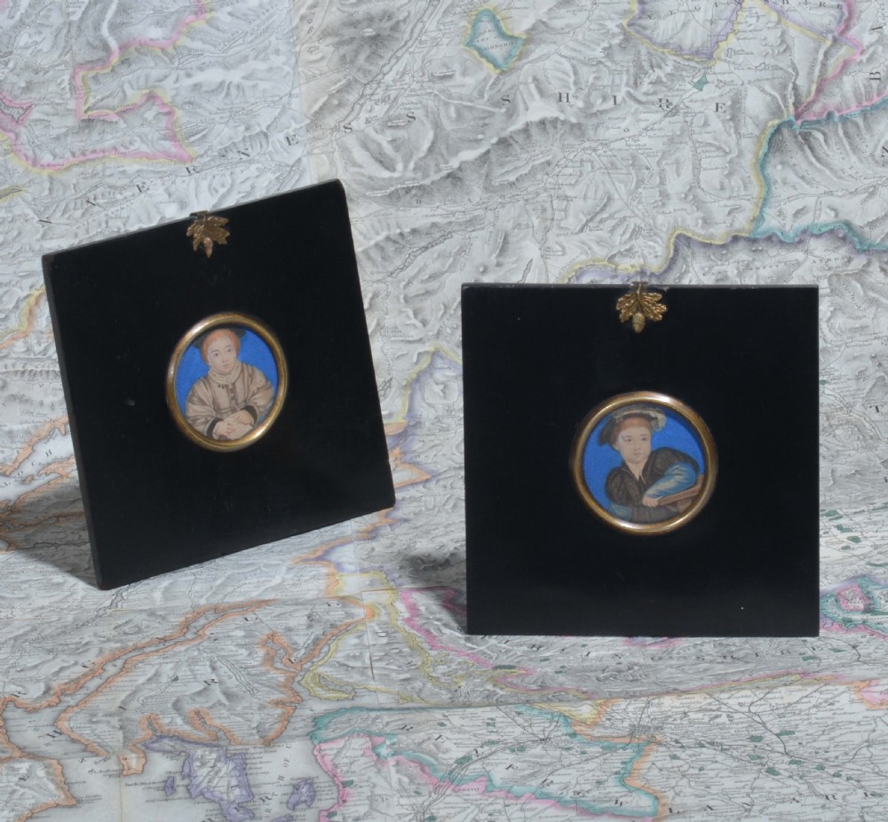 A pair of square ebonised framed portrait miniatures featuring Tudor figures in oval gilt bezels topped with brass acorn hangers.