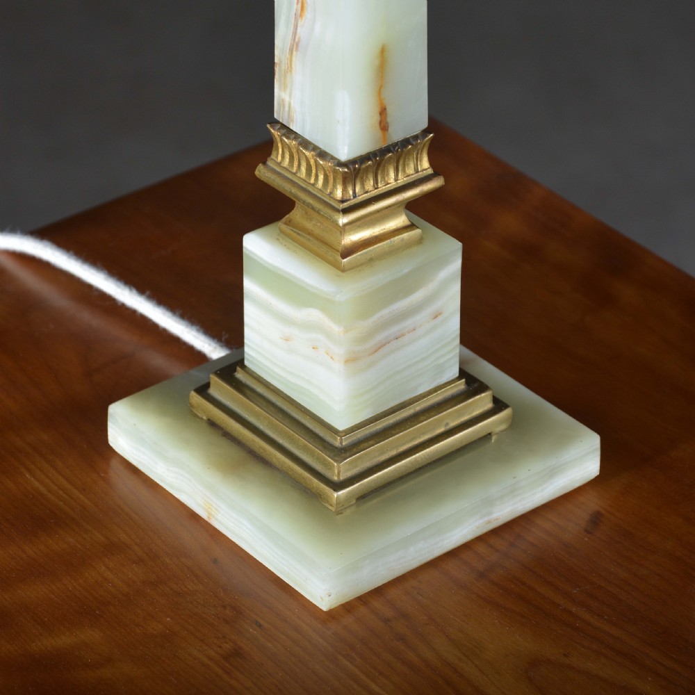 A tapered pale green onyx column table lamp featuring gilt brass collar details and a black fabric lamp shade. View V