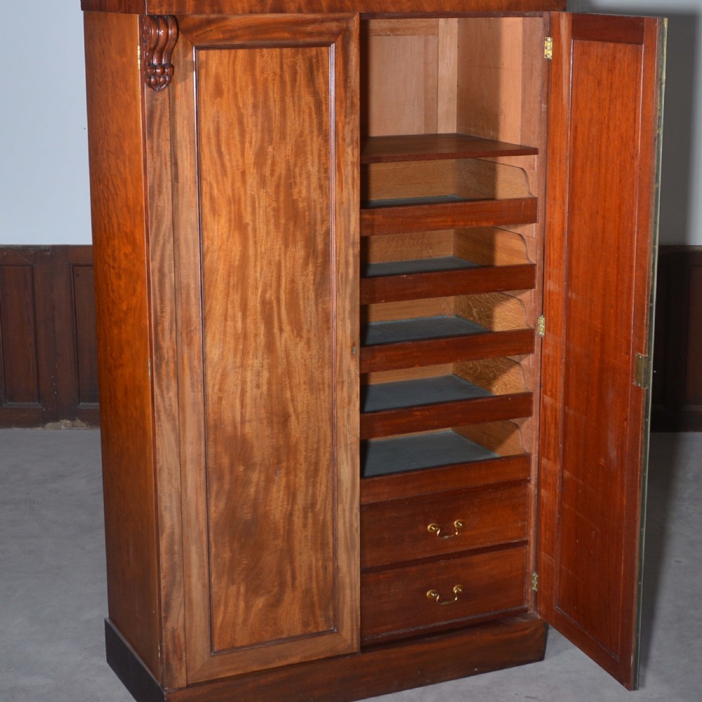 A nineteenth-century Scottish mahogany linen press featuring flame mahogany panelled doors, carved corbel brackets, and a plinth base. View III