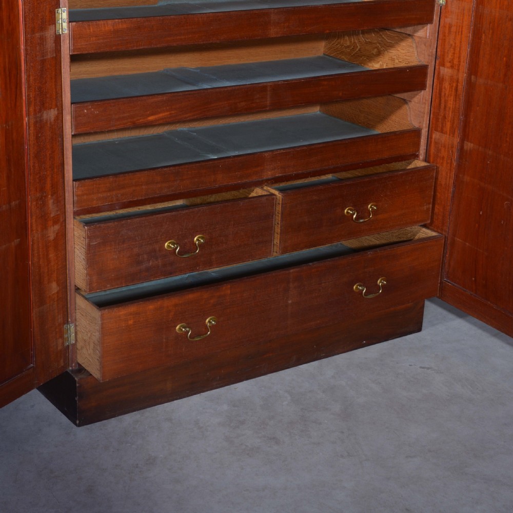 A nineteenth-century Scottish mahogany linen press featuring flame mahogany panelled doors, carved corbel brackets, and a plinth base. View IV