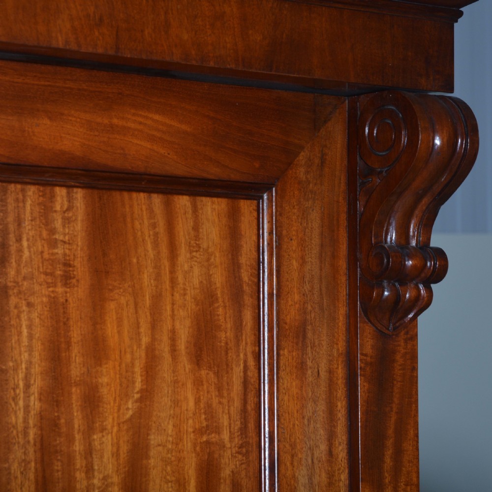 A nineteenth-century Scottish mahogany linen press featuring flame mahogany panelled doors, carved corbel brackets, and a plinth base. View IX