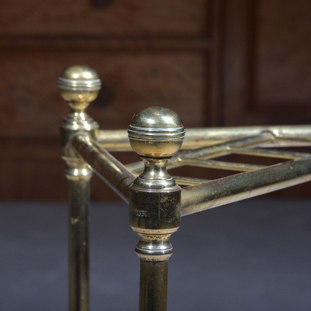 A triangular brass corner stick stand featuring tubular uprights topped with finials and a black cast iron drip tray base. View IV