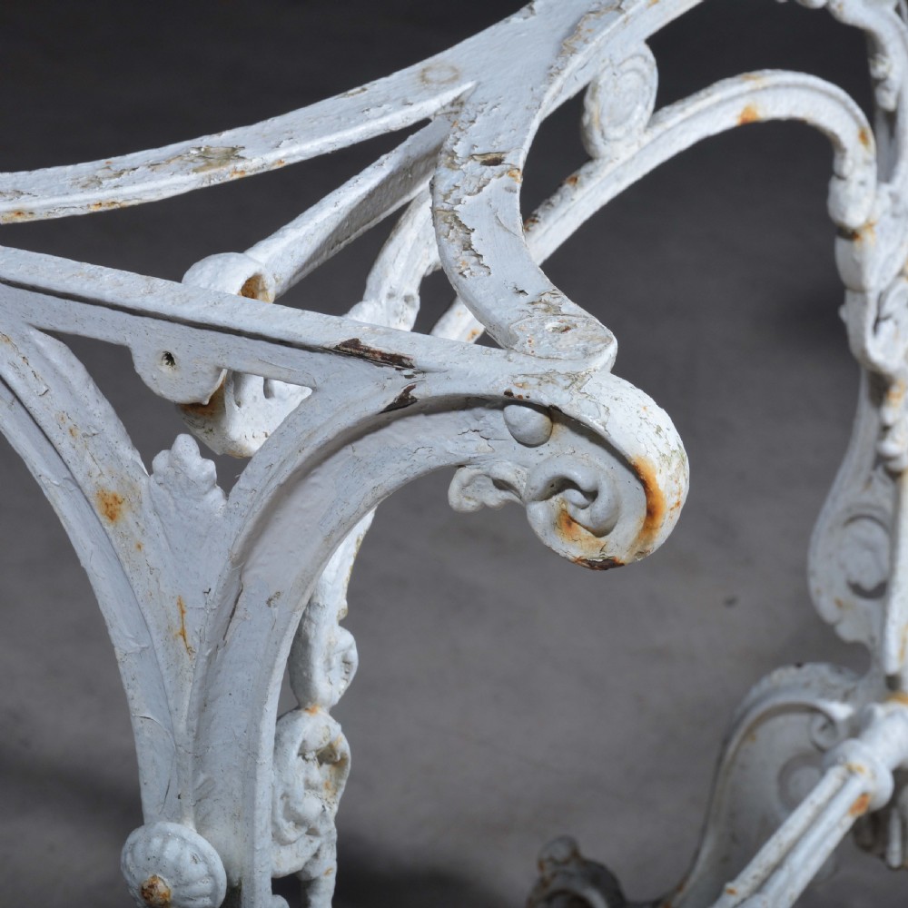 A white painted cast iron table with decorative scrollwork trestle legs and a rectangular grey-veined marble slab top. View VI