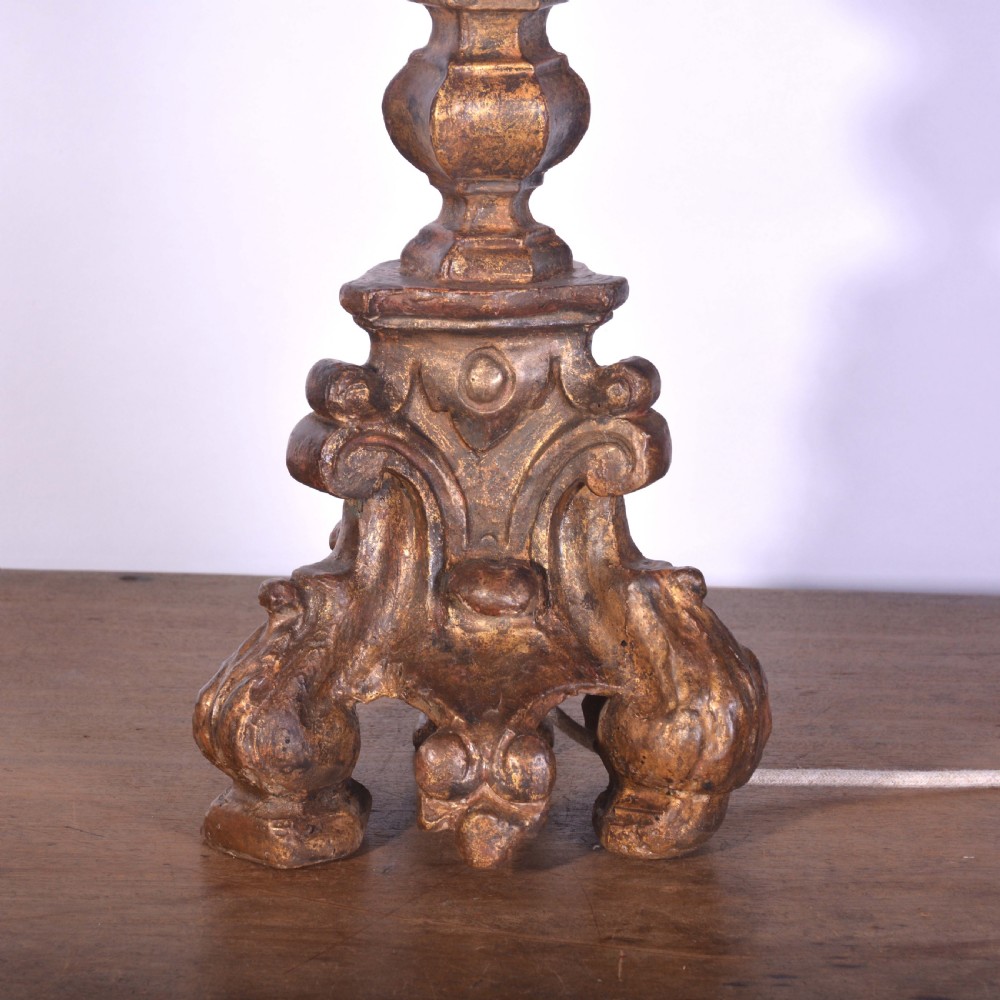 A tall Spanish gilt wood table lamp featuring a turned, carved column base finished in gold leaf, paired with a black flared lampshade. View II
