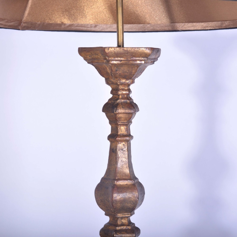 A tall Spanish gilt wood table lamp featuring a turned, carved column base finished in gold leaf, paired with a black flared lampshade. View IV