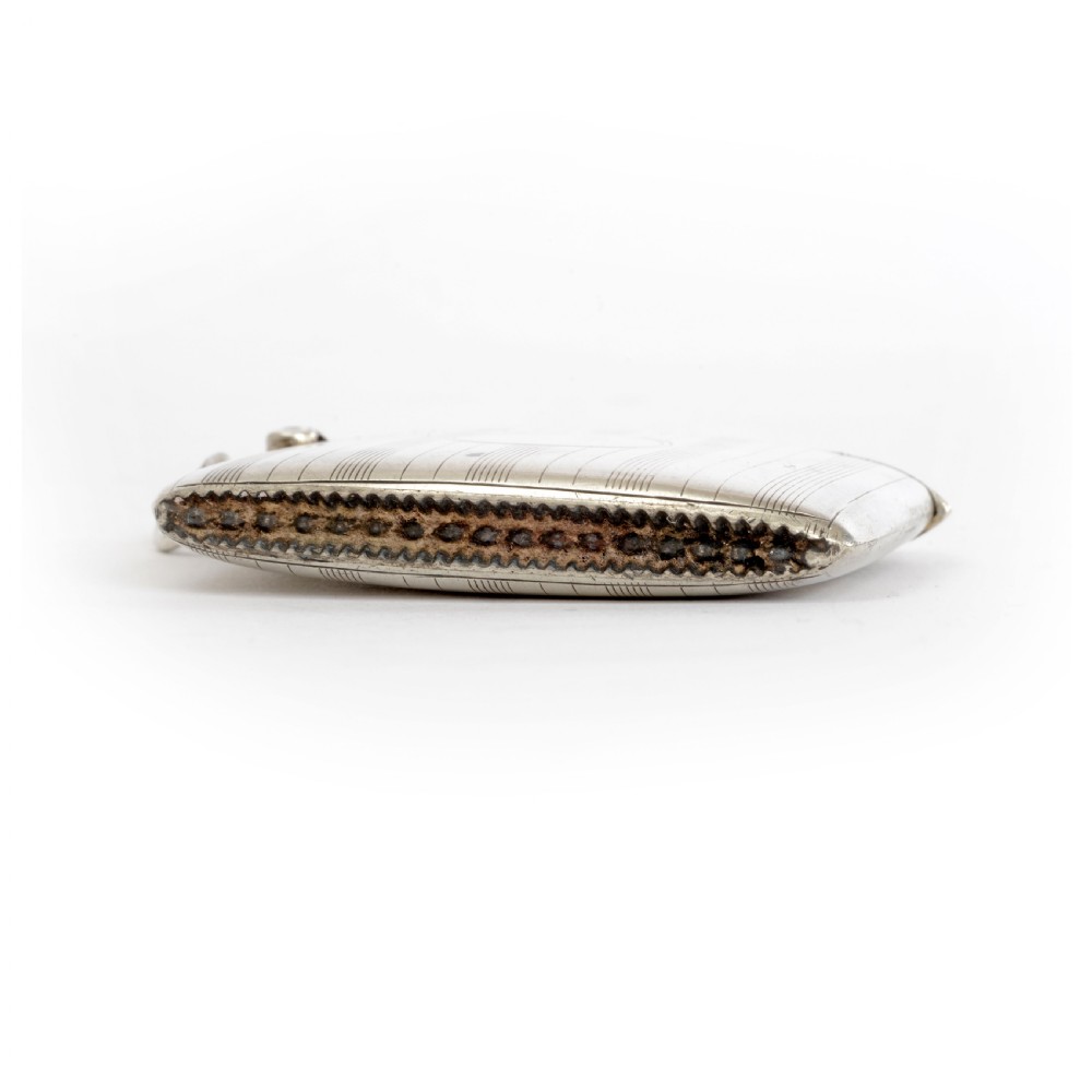 An engine-turned sterling silver vesta case with a circular unengraved cartouche, hinged lid, and side suspension loop against a plain background. View IV