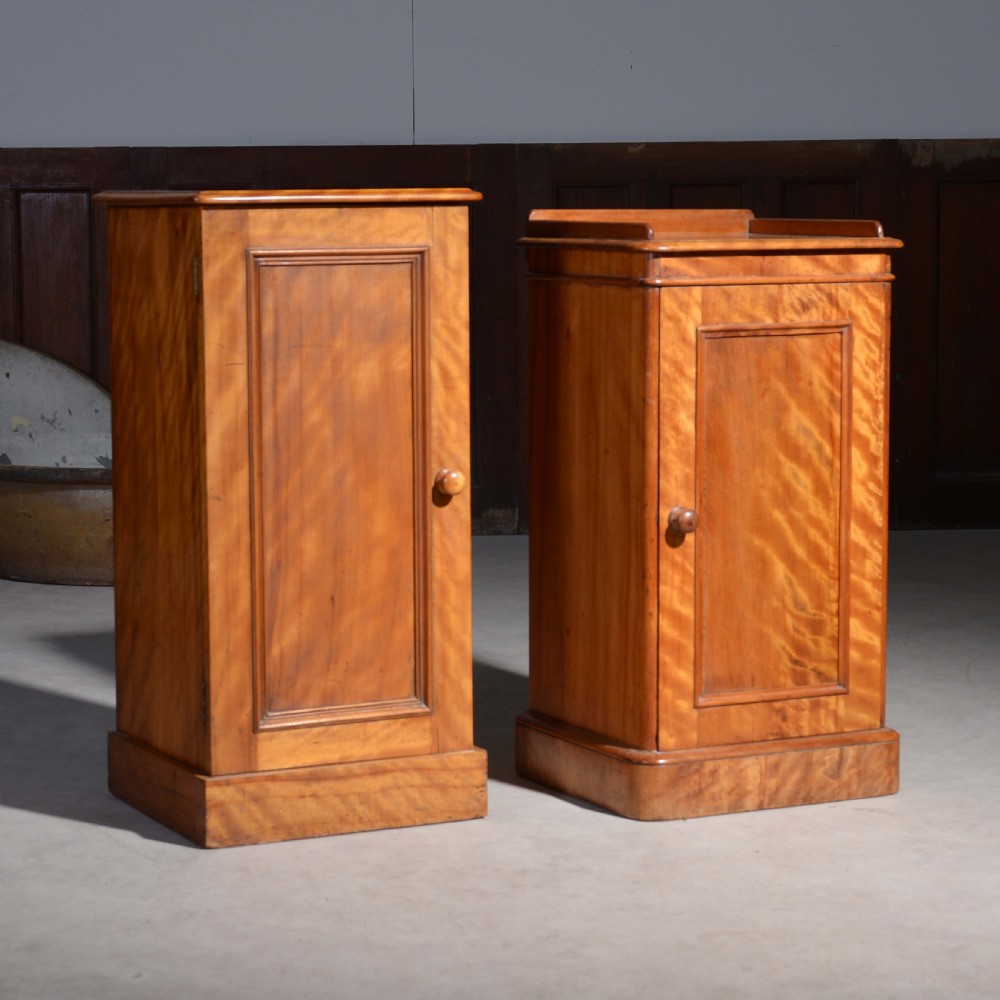 A near pair of Victorian satin birch bedside cabinets featuring single panelled doors, turned timber knobs, and plinth bases. View II