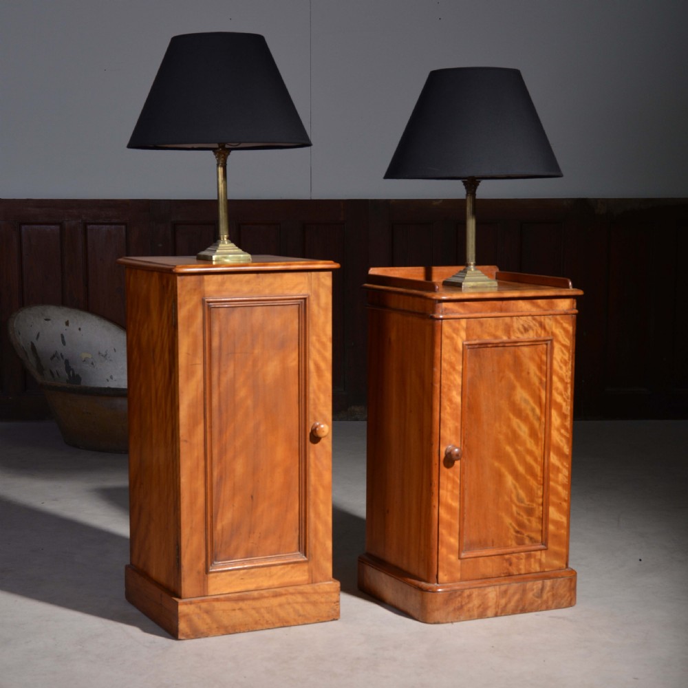A near pair of Victorian satin birch bedside cabinets featuring single panelled doors, turned timber knobs, and plinth bases. View V