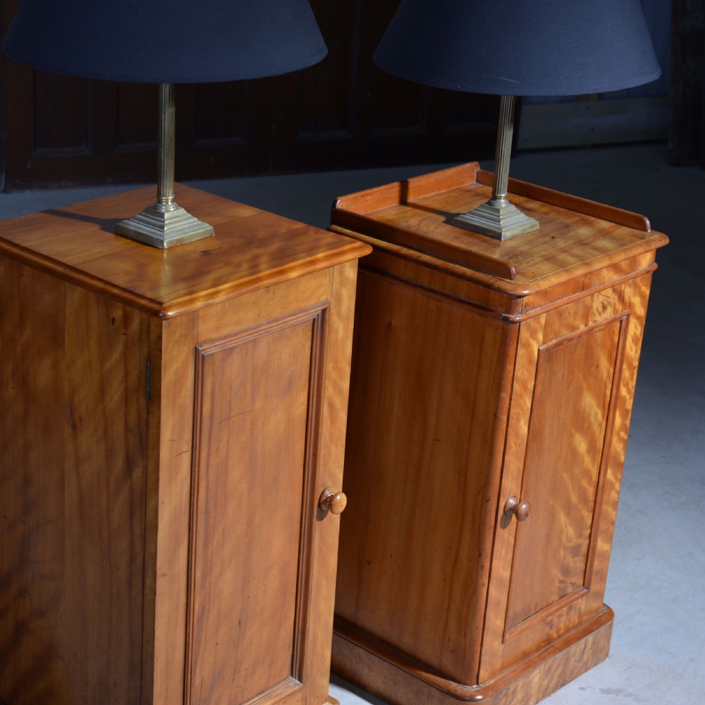 A near pair of Victorian satin birch bedside cabinets featuring single panelled doors, turned timber knobs, and plinth bases. View VI