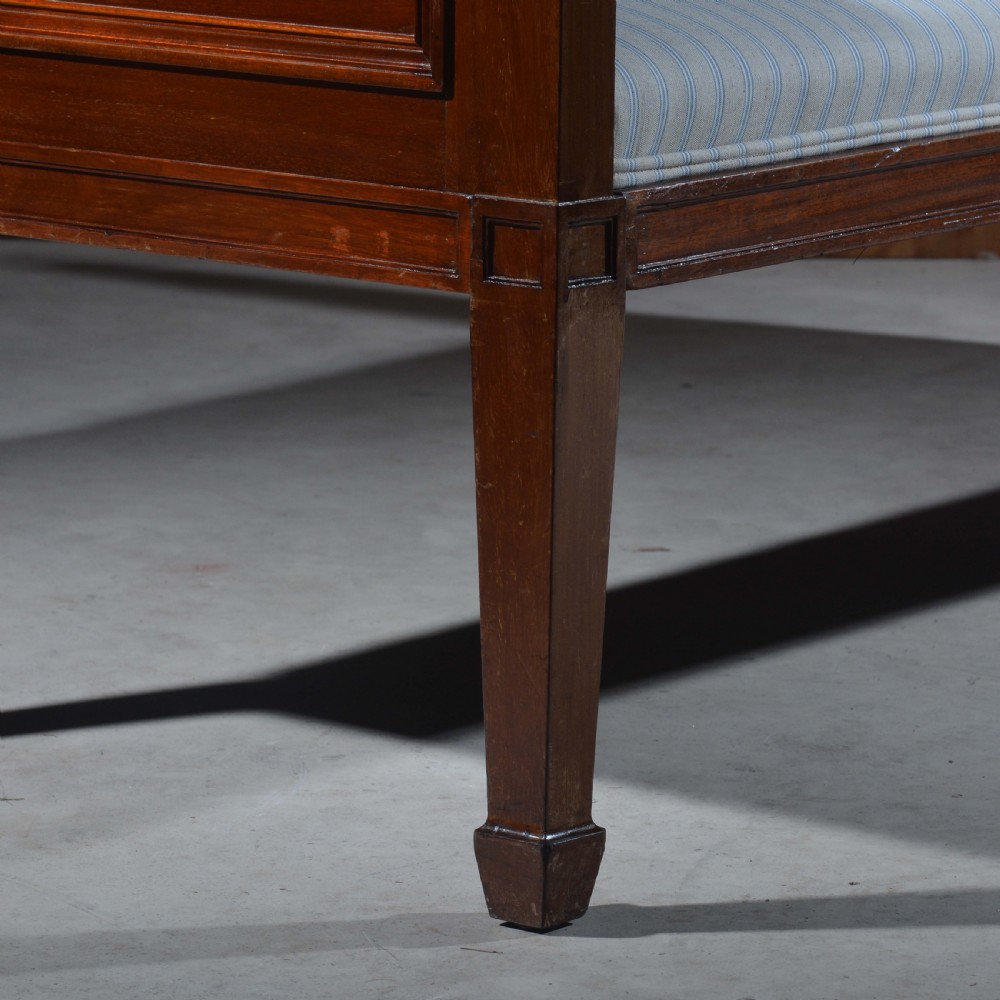 An antique mahogany day bed with panelled endboards, tapered square legs, and a striped light blue upholstered mattress cushion. View VI