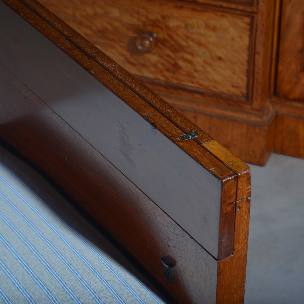 An antique mahogany day bed with panelled endboards, tapered square legs, and a striped light blue upholstered mattress cushion. View VII