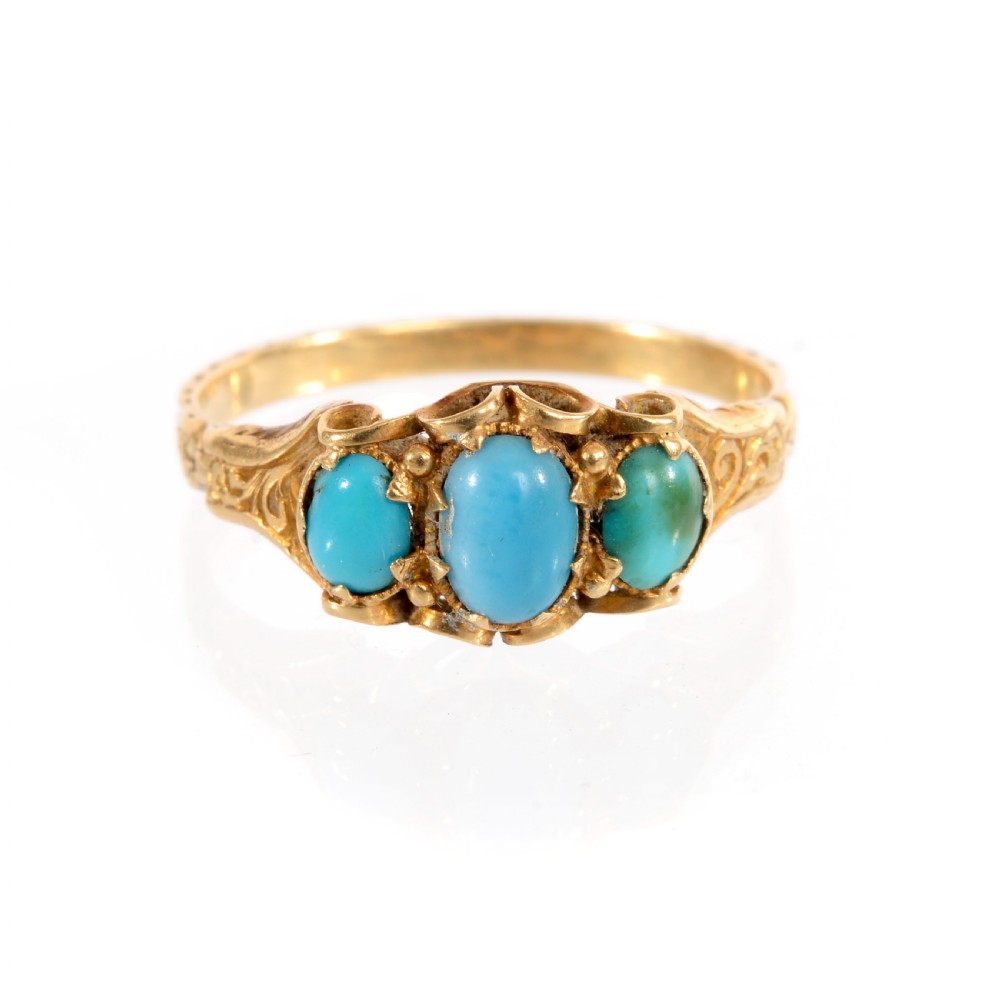 A Victorian yellow gold ring set with three oval cabochon turquoise gemstones featuring scrollwork shoulders. View II