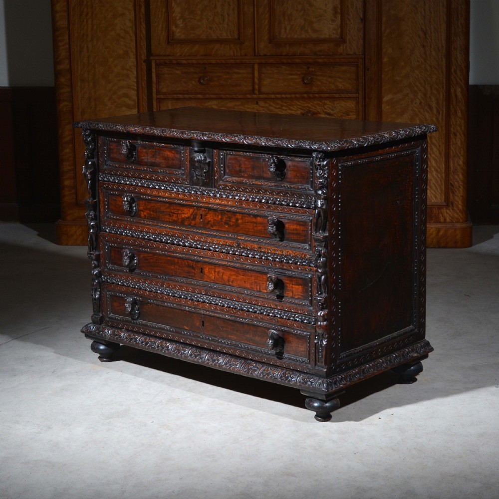A dark carved walnut Italian Renaissance style chest of drawers featuring small carved figural pilasters and turned bun feet. View II