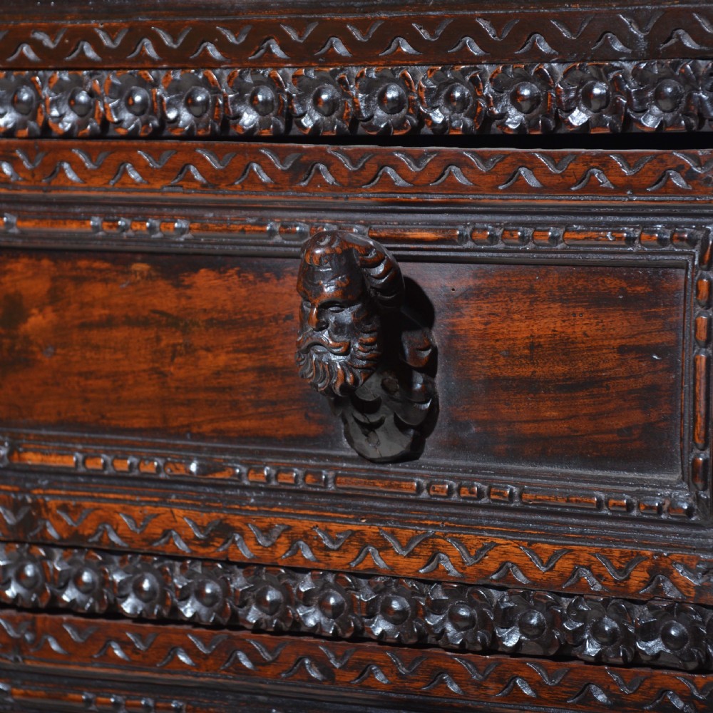A dark carved walnut Italian Renaissance style chest of drawers featuring small carved figural pilasters and turned bun feet. View V