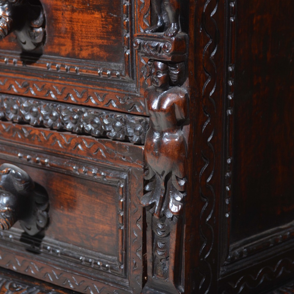 A dark carved walnut Italian Renaissance style chest of drawers featuring small carved figural pilasters and turned bun feet. View VIII