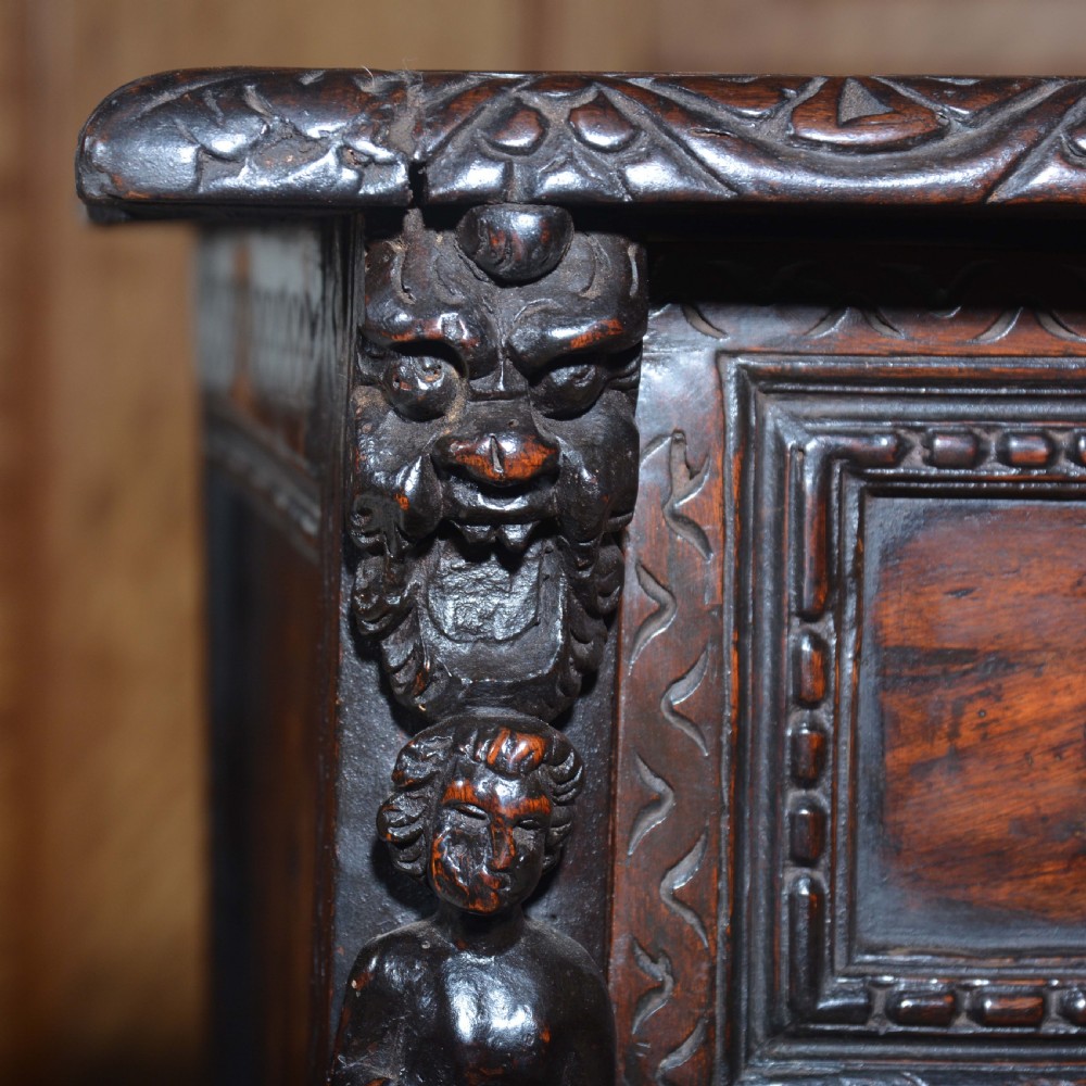 A dark carved walnut Italian Renaissance style chest of drawers featuring small carved figural pilasters and turned bun feet. View X