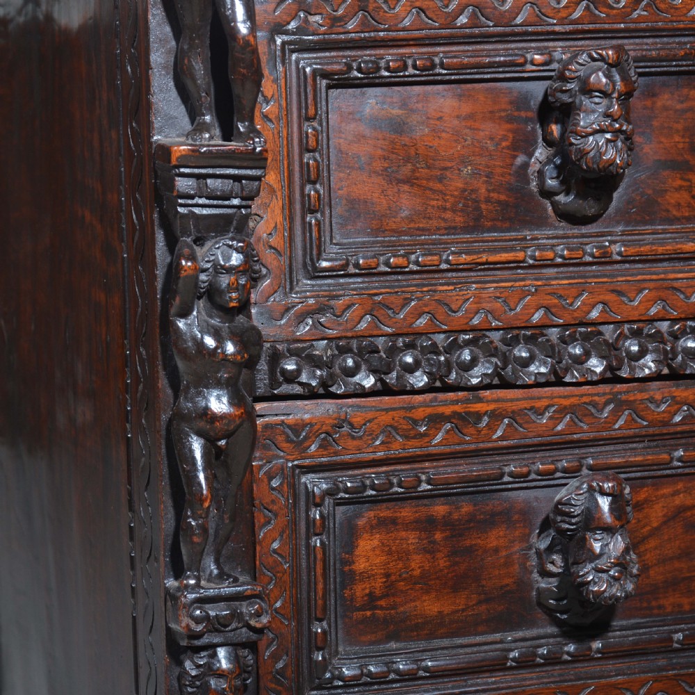 A dark carved walnut Italian Renaissance style chest of drawers featuring small carved figural pilasters and turned bun feet. View XI