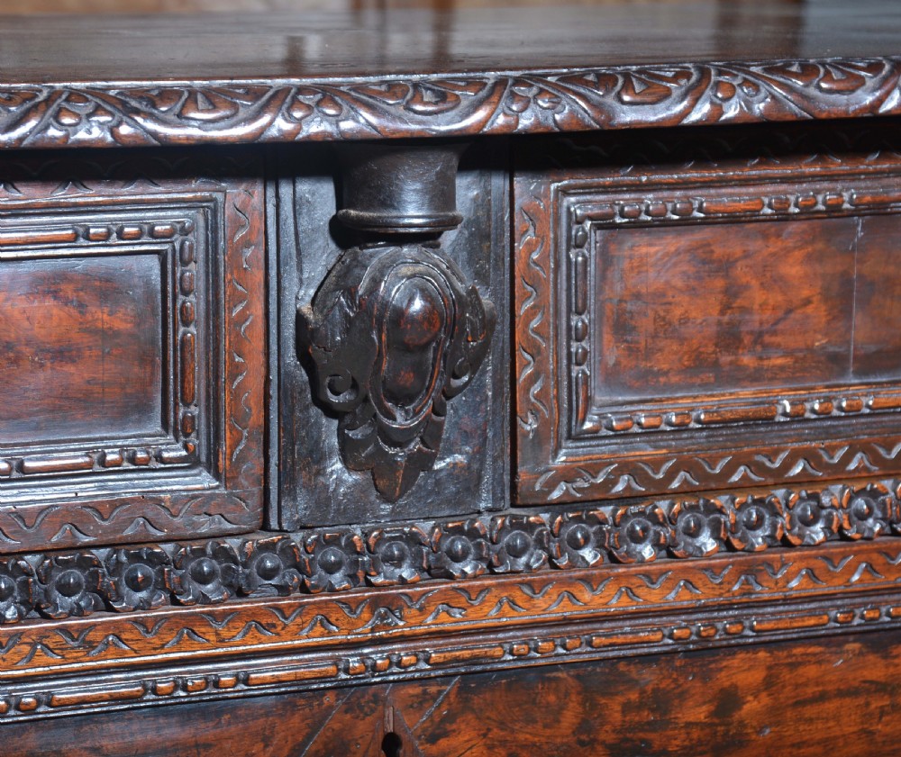 A dark carved walnut Italian Renaissance style chest of drawers featuring small carved figural pilasters and turned bun feet. View XIII