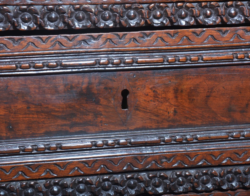 A dark carved walnut Italian Renaissance style chest of drawers featuring small carved figural pilasters and turned bun feet. View XIV