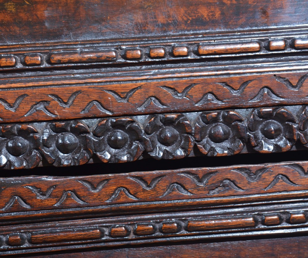 A dark carved walnut Italian Renaissance style chest of drawers featuring small carved figural pilasters and turned bun feet. View XV