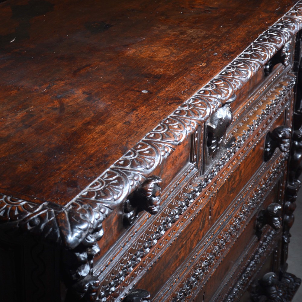 A dark carved walnut Italian Renaissance style chest of drawers featuring small carved figural pilasters and turned bun feet. View XVII