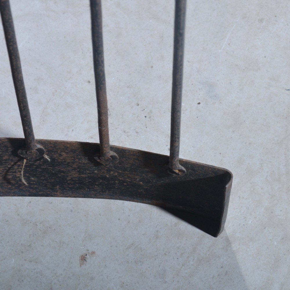 A curved wrought iron nursery fender with closely spaced vertical bars mounted onto a solid metal plinth base. View VI
