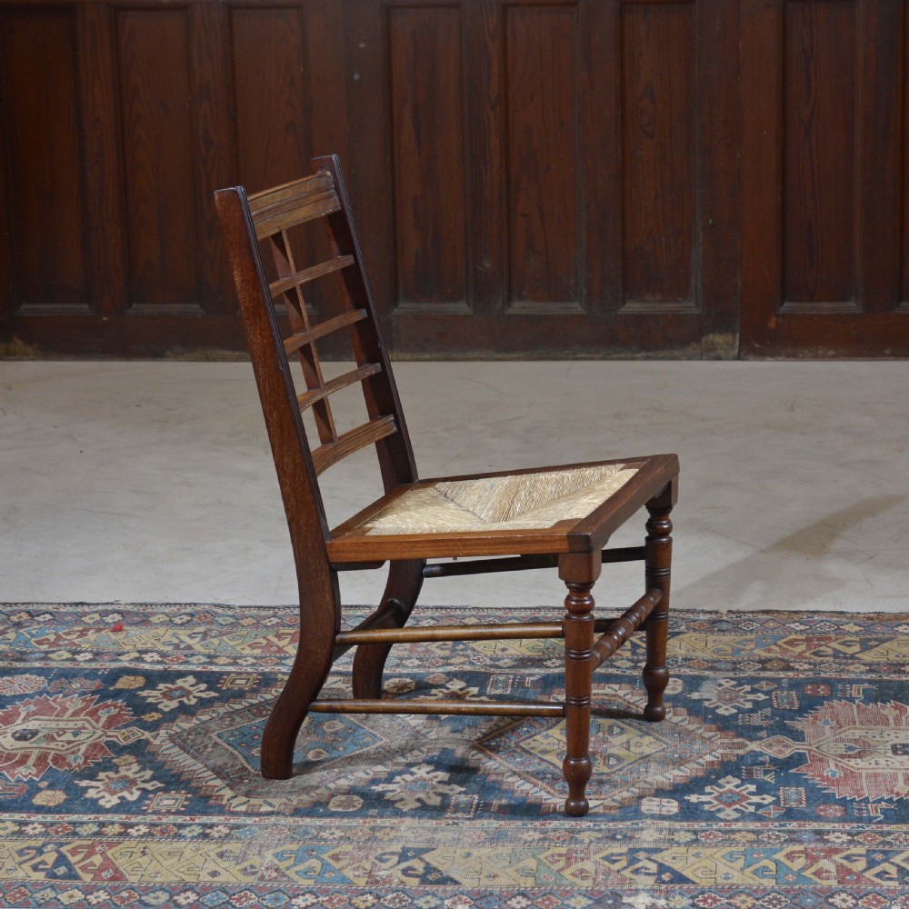 An antique dark oak Aesthetic Movement low side chair featuring a woven rush seat and a slotted backrest with turned legs. View V