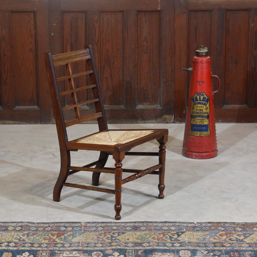 An antique dark oak Aesthetic Movement low side chair featuring a woven rush seat and a slotted backrest with turned legs. View IV