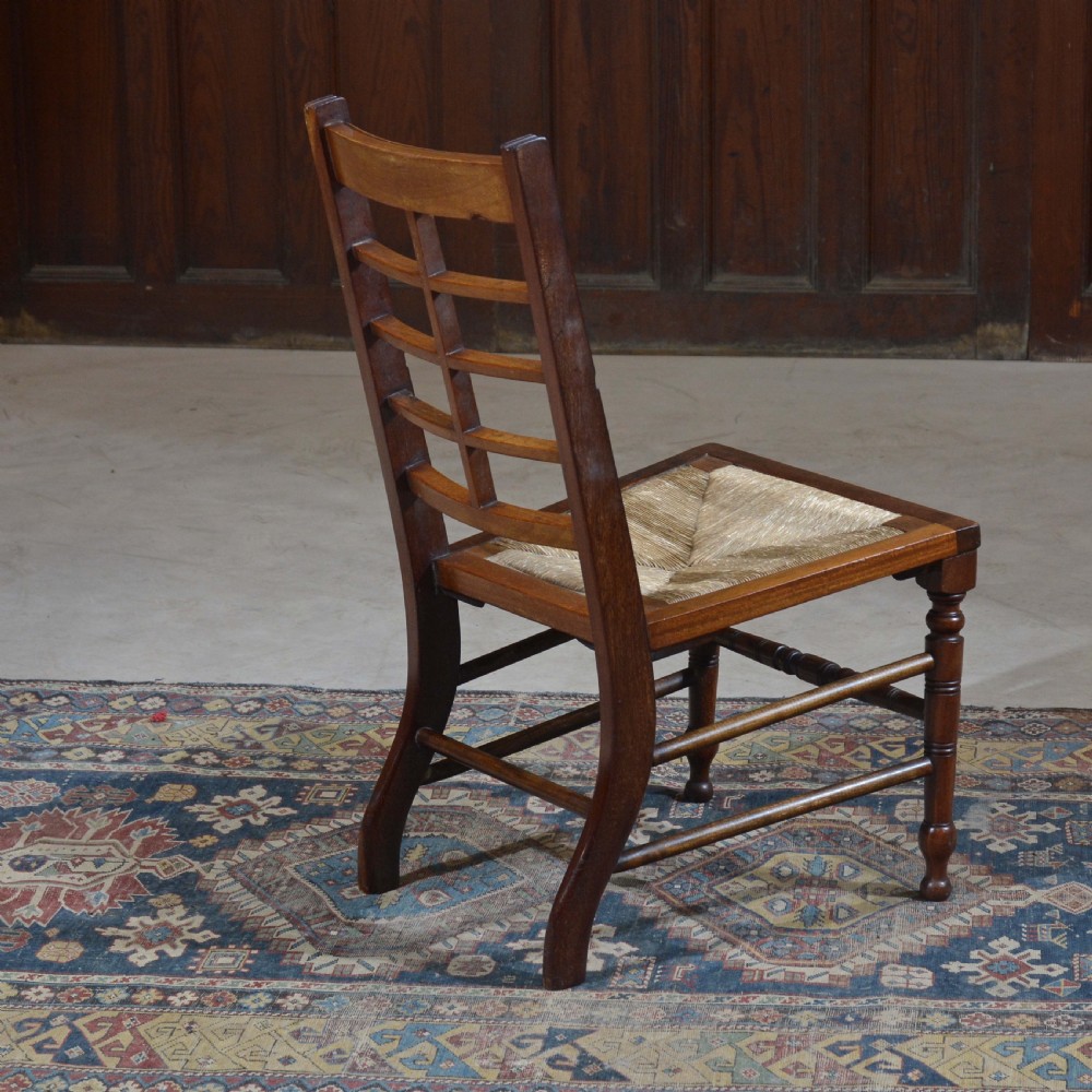An antique dark oak Aesthetic Movement low side chair featuring a woven rush seat and a slotted backrest with turned legs. View VI