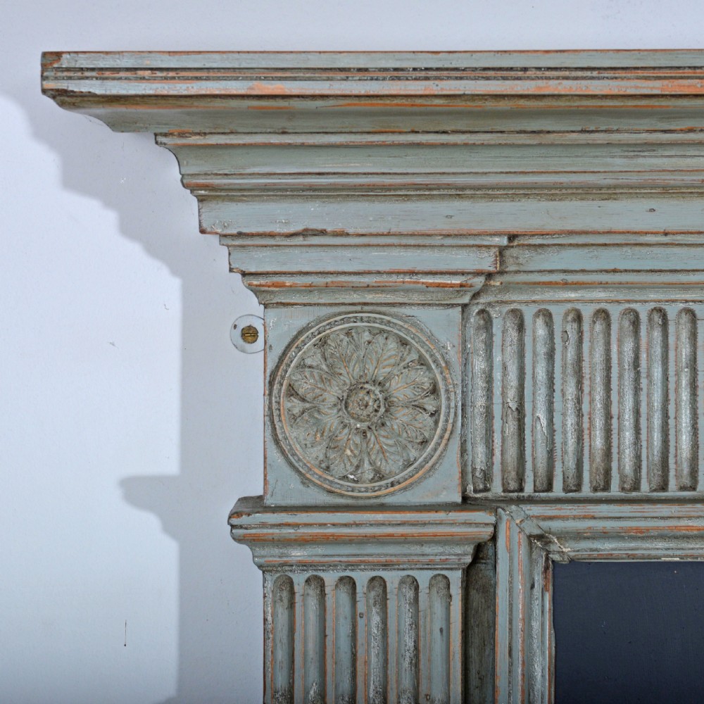A carved Georgian Neoclassical fire surround painted pale blue, featuring fluted pilasters, decorative festoons, and a central urn panel. View VI