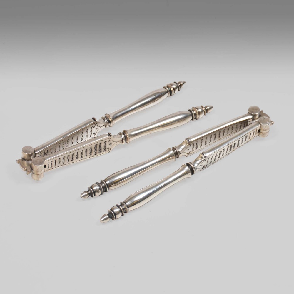 Two pairs of silver-plated lobster crackers featuring turned handles, finial tips, and textured inner serrated jaws.