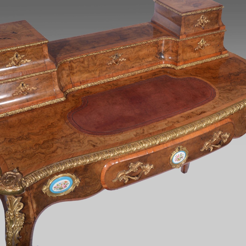 A Louis XV style walnut bureau plat desk featuring a raised superstructure of small drawers, gilt-bronze mounts, floral porcelain plaques, and cabriole legs. View II