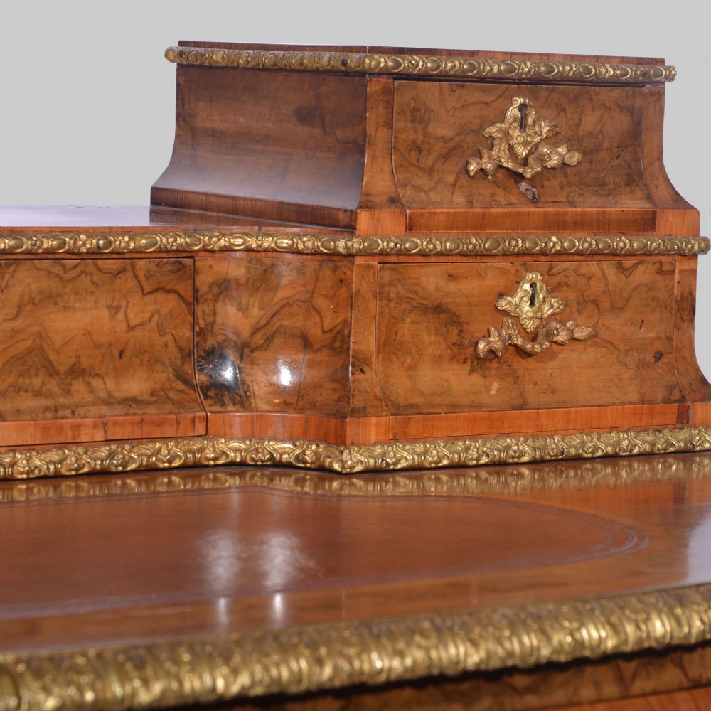 A Louis XV style walnut bureau plat desk featuring a raised superstructure of small drawers, gilt-bronze mounts, floral porcelain plaques, and cabriole legs. View VII