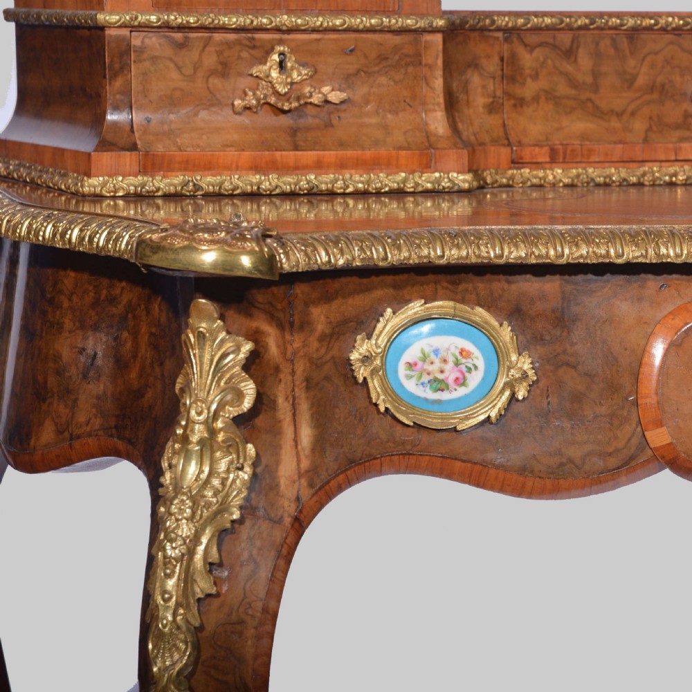 A Louis XV style walnut bureau plat desk featuring a raised superstructure of small drawers, gilt-bronze mounts, floral porcelain plaques, and cabriole legs. View VIII