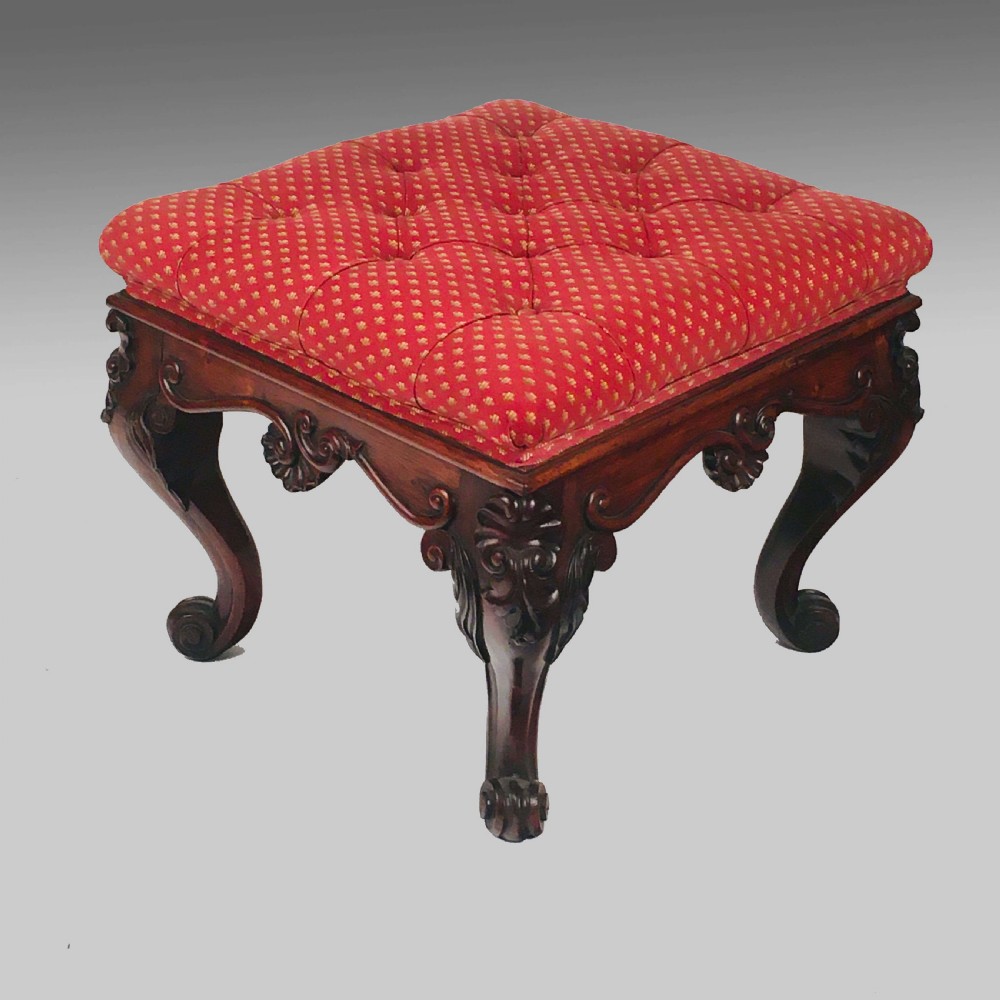 A square antique Anglo-Indian rosewood stool featuring a button-tufted red upholstery seat above intricately carved cabriole legs. View II