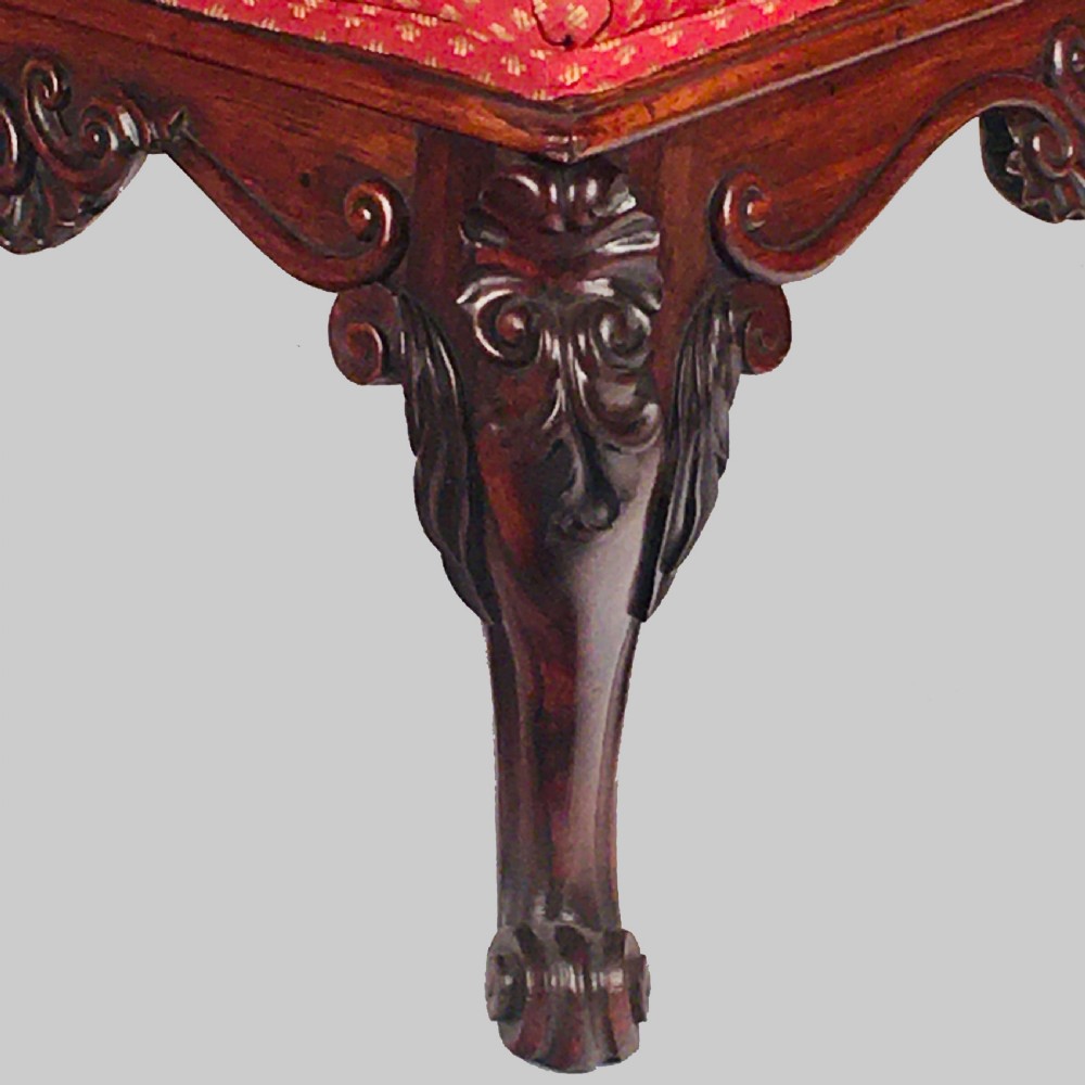 A square antique Anglo-Indian rosewood stool featuring a button-tufted red upholstery seat above intricately carved cabriole legs. View IV