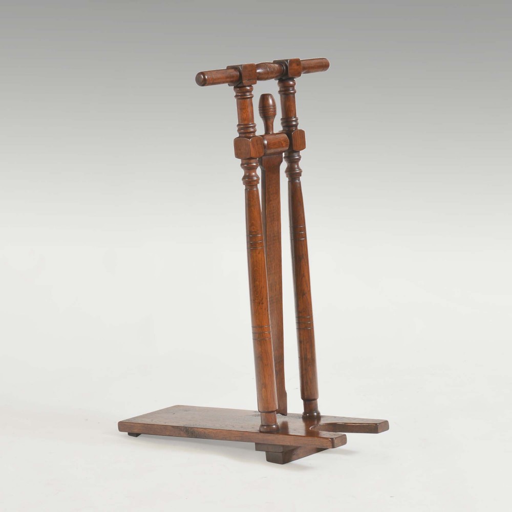 A 19th-century standing wooden bootjack constructed from dark oak and ash with turned twin upright handles and a notched base plate.