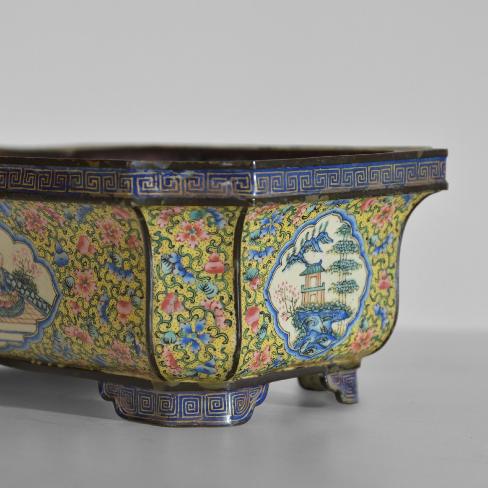 A rectangular antique Chinese Canton enamel jardiniere featuring a yellow floral ground, reserve panels depicting landscapes and figures, and a pink interior. View X