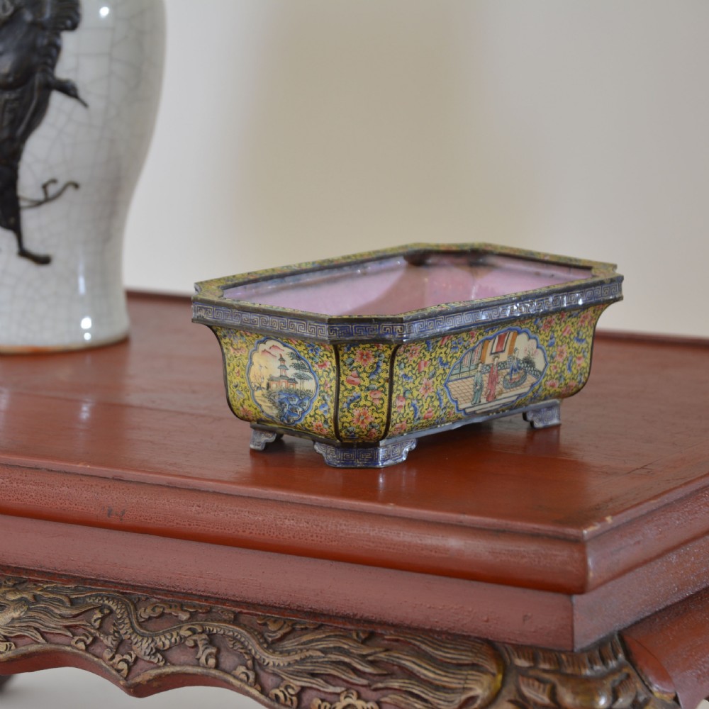 A rectangular antique Chinese Canton enamel jardiniere featuring a yellow floral ground, reserve panels depicting landscapes and figures, and a pink interior. View XII