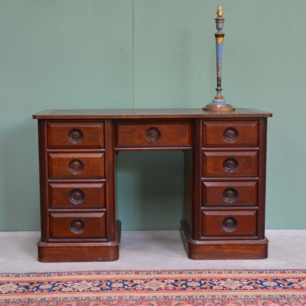 A nineteenth-century mahogany pedestal desk featuring nine moulded drawers with central turned wooden handles resting on plinth bases.