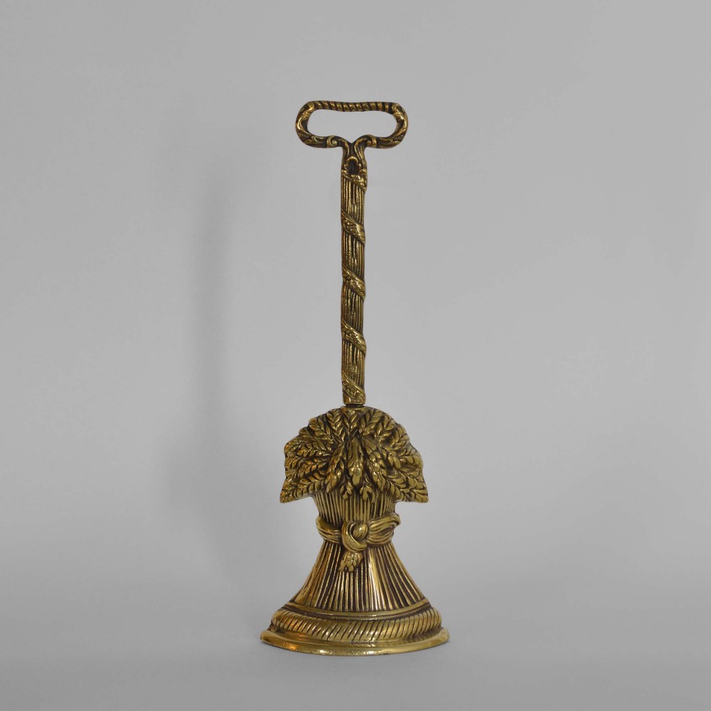 A Victorian cast brass doorstop featuring a wheatsheaf design with a tall twisted stem handle.