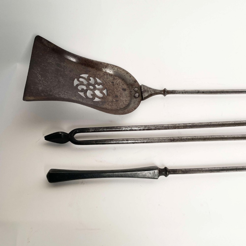 A set of three Georgian fire irons featuring steel shafts and ornate gilt brass foliate handles including a pierced shovel, tongs, and poker. View IV